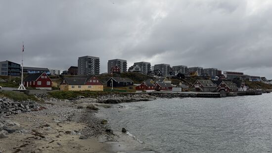 Küstenlinie mit den bunten Holzhäusern im Vordergrund und den modernen Wohnblöcken im Hintergrund