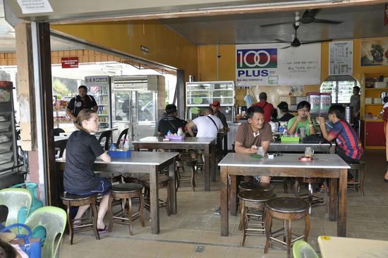 Hier sitzt man und vertreibt sich die Zeit mit essen...im Hntergrund Werbung für "100PLUS" das isotonische Getränk--