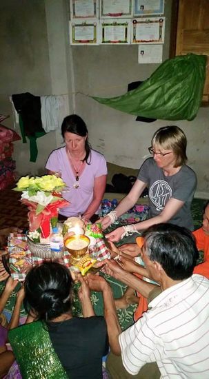 In der Mitte ist eine Schale mit kleinen Präsenten wie Gebäck, Knabbereien, Reis und Whiskey. Wir knien um diese Schale halten sie fest und es wird gebetet