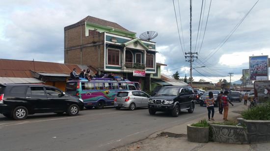 Hinten ein vollbeladener Bus mit Passagieren auf dem Dach
