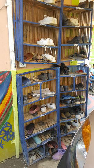 Draußen steht ein großes Regal für die Schuhe der Kinder.
Jedes hat ein Fach mit Namen