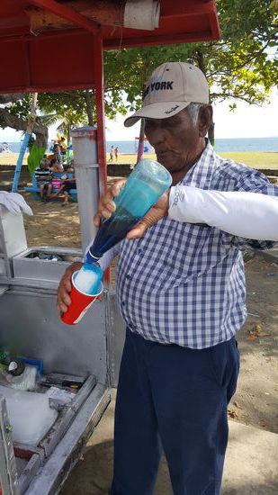 Dann hier eine weitere süße Kalorienbombe , das "Granizado":
Natureis wird von einem großen Block abgekratzt und in einen Becher gedrückt, in dem vorher einige Löffel Milchpulver getan wurden. Dann kommt der süße farbige Sirup auf das Eis und dann noch eine große Menge der gezuckerten Kondensmilch