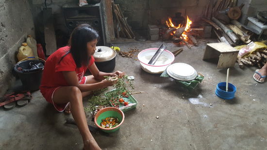 Das Mädel pflückt Knoblauch, kleine Zwiebeln und Pepperoni und wäscht alles