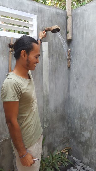 Adhi demonstriert stolz die Dusche: Man achte auf den Duschkopf: eine Kokosnussschale