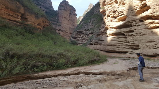 Nach einigen Kilometern verlassen wir die asphaltierte Straße und kommen auf einen unebenen schmalen Erdweg.
Unser Fahrer steigt aus um den Weg zu prüfen, denn es gibt tiefe Furchen vom Wasserlauf.
Hier paßt er gerade so durch. Es ist Millimeterarbeit. Kommt er mit einem Rad in so eine Furche, die ca 15cm tief ist, ist die Fahrt vorbei