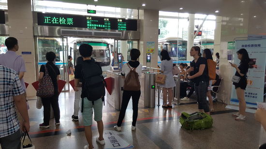 Hier warten wir auf den Bus. Obwohl wieder keiner Englisch spricht, versucht man uns zu helfen und gibt uns zu verstehen, dass der Bus Verspätung hat und sich die Schranke erst kurz vor Abfahrt öffnet