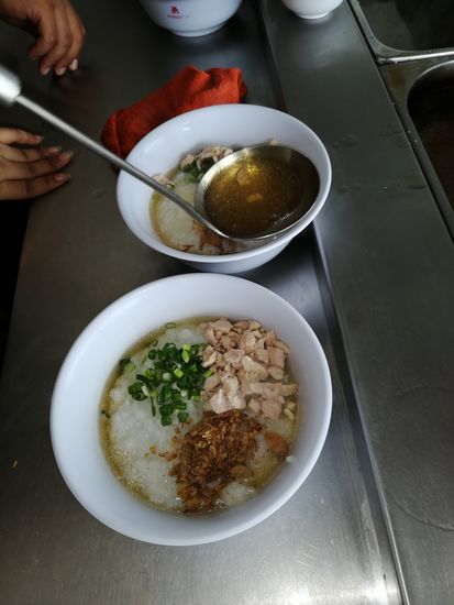 Zu dem Reis gibt es eine Brühe, Hühnerfleisch, Röstzwiebeln und frische Lauchzwiebeln