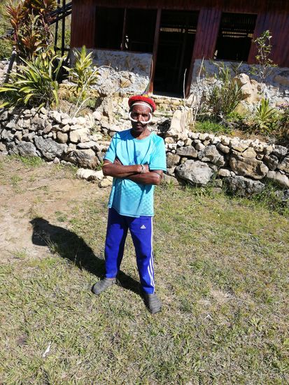 Er holt den traditionellen Kopf und Nasenschmuck hervor und präsentiert sich damit