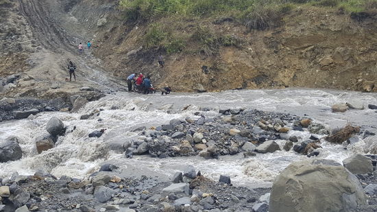 Dort schieben und ziehen ein paar Männer ein schweres Motorrad durch die Fluten