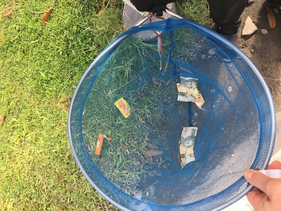 An der Straße stehen Jungs, die Geld zugeworfen bekommen und es mit einem Netz einfangen