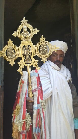 Vor dem Eingang der Felsenkirche steht der Priester und zeigt uns verschiedene Kreuze