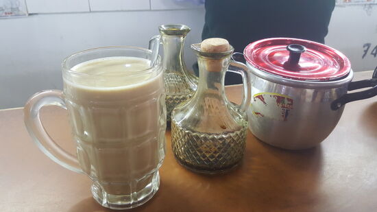 Ich nehme einen Milchkaffee. Dazu bekomme ich einen großen Pott heiße Milch mit Schaum, den Omi aus einem großen Blechkochtopf schöpft. Dann darf ich mir aus den Glaskaraffen, die auf dem Tisch stehen, Kaffeekonzentrat nach Belieben eingießen. In dem kleinen Blechtopf ist Zucker. Übrigens gibt es hier ausschließlich braunen Zucker.