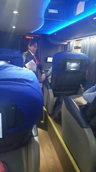 Eine flott  gekleidete „Stewardess“ kommt herum, vergleicht die Namen und fragt, ob es uns gut geht oder noch etwas brauchen—Decke und Kissen sind vorhanden—TV ist uninteressant, da die Filme nur in spanisch sind