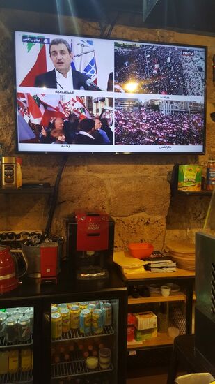 Innen läuft der Fernseher—natürlich Thema No1: die Aufstände und die Revolution.
Das Mädel zeigt auf ein Bild und in die Richtung Zentrum auf dem Berg—da ist auch was los! Da wir eh noch zum Supermarkt müssen, wollen wir uns das näher anschauen