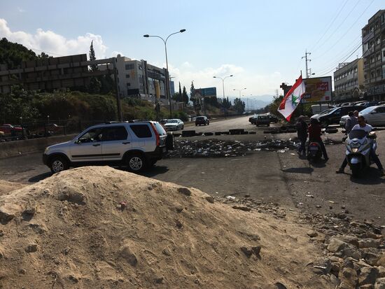 Wie schon erwartet: Straße mit Sand und verkohlten Reifen versperrt.
Überall Menschen, welche die libanesische Fahne schwenken