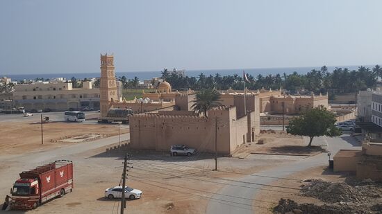 Von oben der schöne Blick auf die Moschee von Taqa und das Meer mit Palmen
