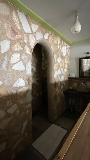 Hinter der Natursteinwand befinden sich Dusche und Wc-davor das Waschbecken