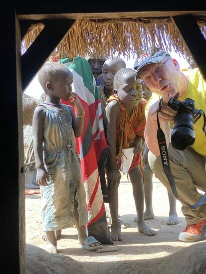 Während ich mich durch die kleine Eingangstür gequetscht habe, bleibt Thomas vor der Hütte und ist umlagert von vielen interessierten Kindern