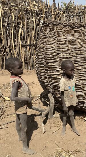Interessierte Beobachter. In diesem großen Korb werden Lebensmittel aufbewahrt - und die Saat, die nach der Regenzeit, die in den nächsten Tagen kommen wird, in den Boden kommt.