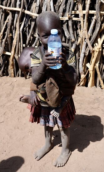 Das kleine Mädchen bekommt von Thomas eine Wasserflasche. Das ist hier etwas sehr Kostbares.
