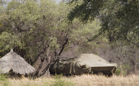 Zwischen den Hütten stehen abgedeckte Panzer