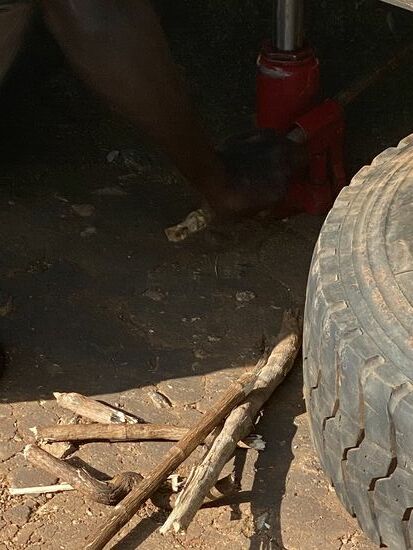 ….legen diesen unter für den Fall, dass der Wagenheber „flöten“ geht und der Wagen sanft landet.
Ich suche in der Wildniss einen Stein zum unterlegen, weil die Höhe des Wagenhebers nicht ausreicht und Denis sucht Holzstöcke als Ersatz für den Metallhebel, da braucht er einige, da diese natürlich immer wieder zerbrechen