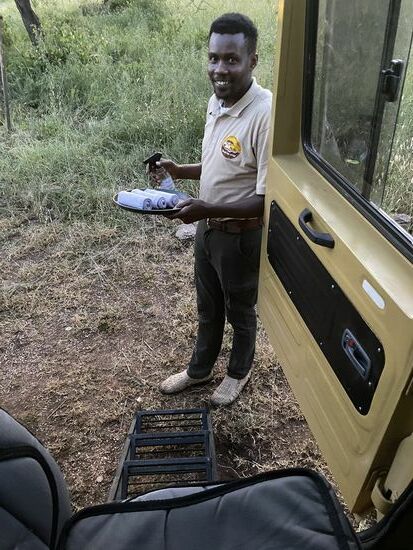 Wir werden mit einem Lächeln im Gesicht, Jambo Jambo (Hallo Hallo), feuchten heißen Tüchern und Desinfektionsmittel begrüßt.
Sogar eine Leiter stellt man uns an das Fahrzeug