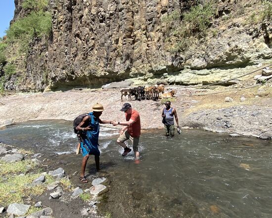 Kelvin muss uns einige Male bei der Flussüberquerung helfen und schon nach wenigen Metern trägt er den schweren Fotorucksack von Thomas