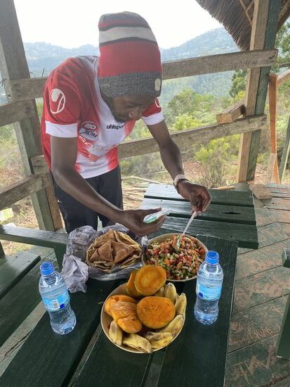 Es gibt Avocado, Zwiebeln, Tomaten vermischt, die wir in die Chapati einwickeln und einige Fleischtaschen. Dann Obst zum Nachtisch.
Während wir essen beginnt es zu regnen und wir können erst einmal etwas ausruhen. Die Reste unseres Essens gebe ich an einige Frauen, die am Gipfel mit Bauarbeiten beschäftigt sind. Sie freuen sich sehr darüber.