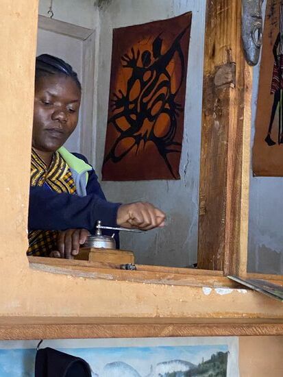 Irgendwann hat sich diese junge Frau dann doch bequemt und sich vom Computer losgeeist und das Kaffeemahlen übernommen, Hier werden die Bohnen noch per Hand gemahlen, mit einer richtig alten Kaffeemühle  - Die Mühle und einen Filter hat ein Freund aus Deutschland mitgebracht.