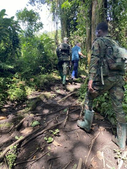 Nach ca. 2 km treffen wir auf eine Gruppe Soldaten. Diese haben auf uns gewartet.  Vier bewaffnete Soldaten werden uns heute begleiten. Wir betreten jetzt den Nationalpark, in dem auch eine Vielzahl wilder Tiere leben: Elefanten, Buffalos, etc. - vor diesen sollen uns die Soldaten beschützen. Wir bewegen uns aber auch unmittelbar (ca. 1-2 km) von der Grenze zum Kongo entfernt. Die Sicherheit der Besucher ist dem Nationalpark und der Regierung sehr wichtig. Aus dem Kongo sind schon mal Rebellen und Wilderer in dieses Gebiet gekommen. Unsere Eskorte soll uns beschützen.