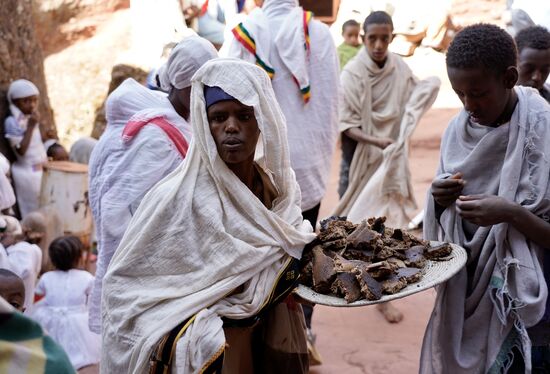 Ein junger Mann kommt mit einem Teller, auf dem Brot ist, aus einer der Kirchen und verteilt es an die Umstehenden. Dieses ist „Holy Bread“ - alle greifen ergriffen zu.