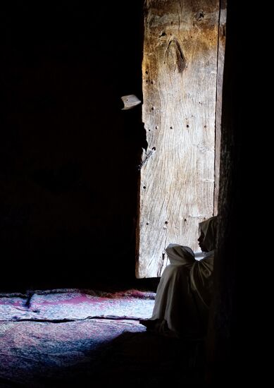 Schweigsam sitzt diese junge Frau neben der Tür und liest in einem Buch.