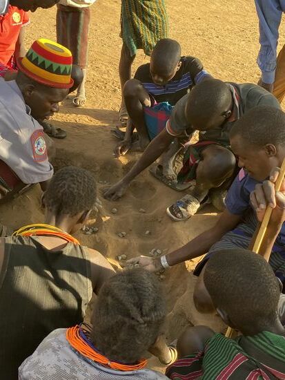 Auf jeder Seite sitzen heute 4 Spieler und spielen gegeneinander. Das Spiel kann Stunden dauern. Verstanden haben wir es nicht. Man war auch nicht wirklich interessiert, das Spiel zu unterbrechen, um es uns zu erklären. Wir glauben, dass es eine Art Roulette ist. Jeder Spieler legt in seine Mulde eine bestimmte Anzahl Steine, in einer Mulde sind die Steine durch Sand verdeckt. Sie werden dann freigewischt. Alles geht sehr schnell.