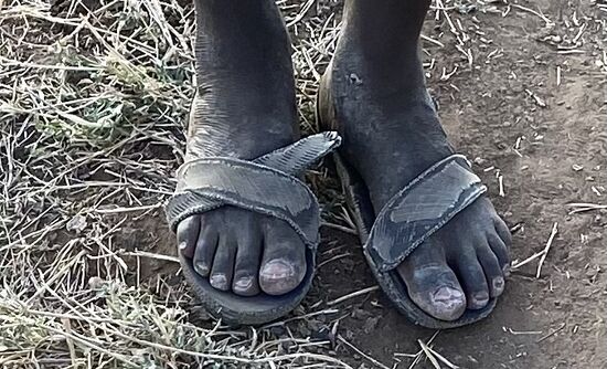 Beim näheren Hinsehen erkennen wir, dass es sich hierbei um alte Autoreifen handelt. Alle Bewohner tragen diese selbstgemachten Schuhe als Schutz vor Schlangen.