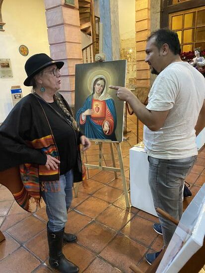 Hinten im Mittelschiff hat ein Künstler aus Peru eine Ausstellung. Er hat auch seine Werkstatt zurzeit hier aufgebaut. Er bietet Claudia an, es doch auch einmal zu probieren. Er hat kleine Leinwände, die man bemalen kann.