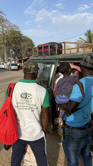 Dawda nimmt das behinderte Mädel auf den Arm und albert mit ihr rum—er hat ein großes Herz. Die Mutter war Kräuter sammeln und will diese zum Markt bringen. Sie ist wirklich schwer beladen
