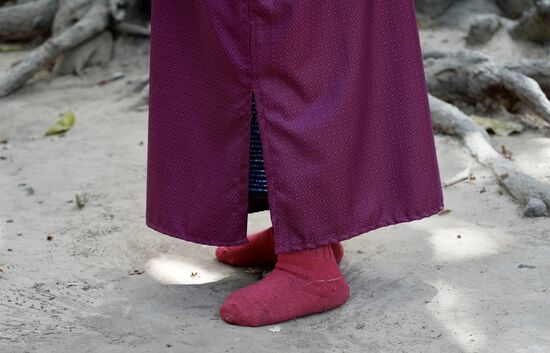 Er trägt ein schlichtes Gewand und Sportsocken ohne Schuhe.