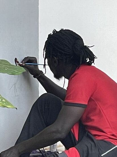 Dawda macht sich ans Werk und bemalt eine Hauswand