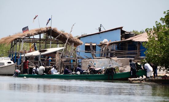 Unsere „Cruise“ geht dem Ende zu und wir paddeln zum Ausgangspunkt. Hier sehen wir den Grenzübergang von Gambia nach Senegal. Autos können hier nicht verladen werden. Hin und wieder sehen wir, wie ein Moped verladen wird. Vollbeladene Fahrzeuge werden entladen und die Waren auf das Boot gebracht. An der anderen Uferseite (ca. 100 Meter) wird entladen und auf ein anderes Fahrzeug verladen. Viele Senegalesen kommen zum Shoppen nach Gambia. Das Angebot ist hier größer und die Preise sind niedriger.