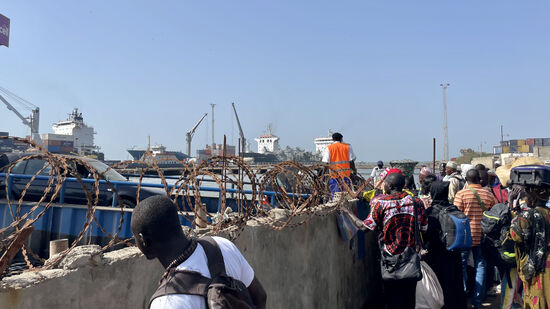Dawda trifft einen Freund—er scheint überall und viele Freunde zu haben.
Eine alte Frau kommt und bettelt. Dawda und sein Freund geben ihr je 20 GMD