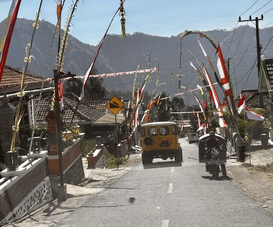 Vom 31. Juli bis 09. August ist eine hinduistische Feierlichkeit, das sogenannte „Karo“. 
Deshalb sind die Straßen geschmückt.
Hier rechts finde ich einen kleinen Warung, wo ich nach einigem Hin- und Her 2 Kaffee zum Mitnehmen bekomme und auch etwas Gebäck