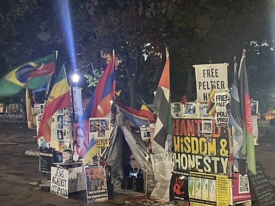 Hier „Wohnt“ ein Demonstrant—er hat sich aus unzähligen Protestartikeln eine „Bude“ gebaut, hockt darin und hat laute Protestmusik an. Reichlich Polizeiaufgebot gibt es hier überall, aber man ignoriert ihn