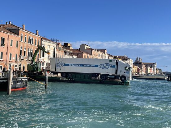 Im Zentrum Venedigs gibt es nur schmale Gassen und keinen Autoverkehr. Alles muss mit Schiffen bzw. Fähren transportiert und angeliefert werden. Hier ein LKW auf Ponton-Fähre. Entladen wird mit einem Bagger.