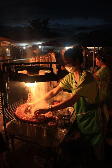 Eine Frau beim Auslegen von Wurstketten auf dem Grill. Thais stehen anscheinend auf gegrillte Wuerstchen (es gibt sie ueberall), uns haben sie leider nicht so gut geschmeckt, haben sie allerdings auch nur einmal probiert