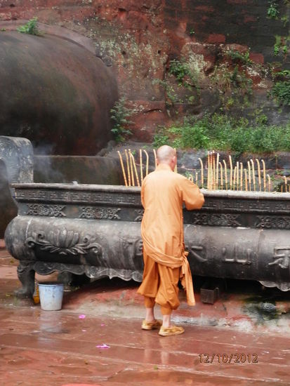 der Moench entzuendet seine Gebetskerze am grossen Zeh des Buddhas...