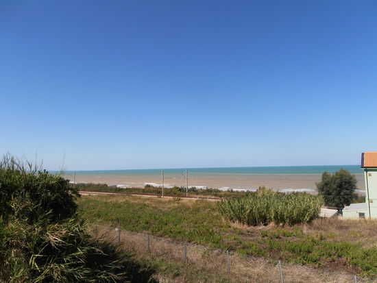 Ein blauer Himmel und eine stürmische See. Man kann den braunen Streifen erkennen, das ist kein Strand sondern aufgewühlte See
