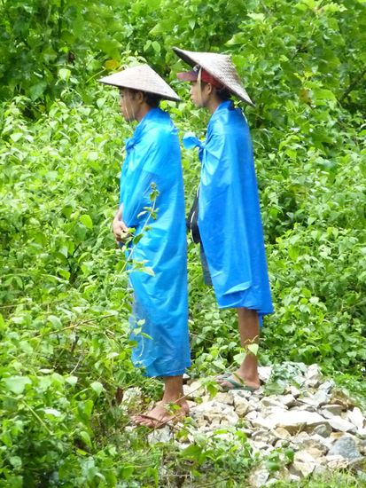 2 Laoten - geschützt von 2 Mülltüten und "Spezialhüten". Man merkt den vietnamesischen Einfluss. Sie bestaunen den immer höher werdenden Wasserpegel. Ein herrliches Bild! Wir amüsieren uns köstlich und sie schauen verwirrt zu uns rüber.