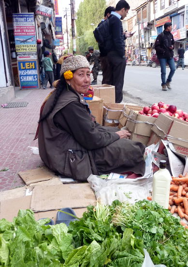 Eine Frau vom Land bietet ihre Ware auf dem Bürgersteig an.