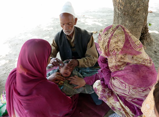 Ein Geistlicher rasiert dem Baby den Kopf, damit die Haare geopfert werden können.